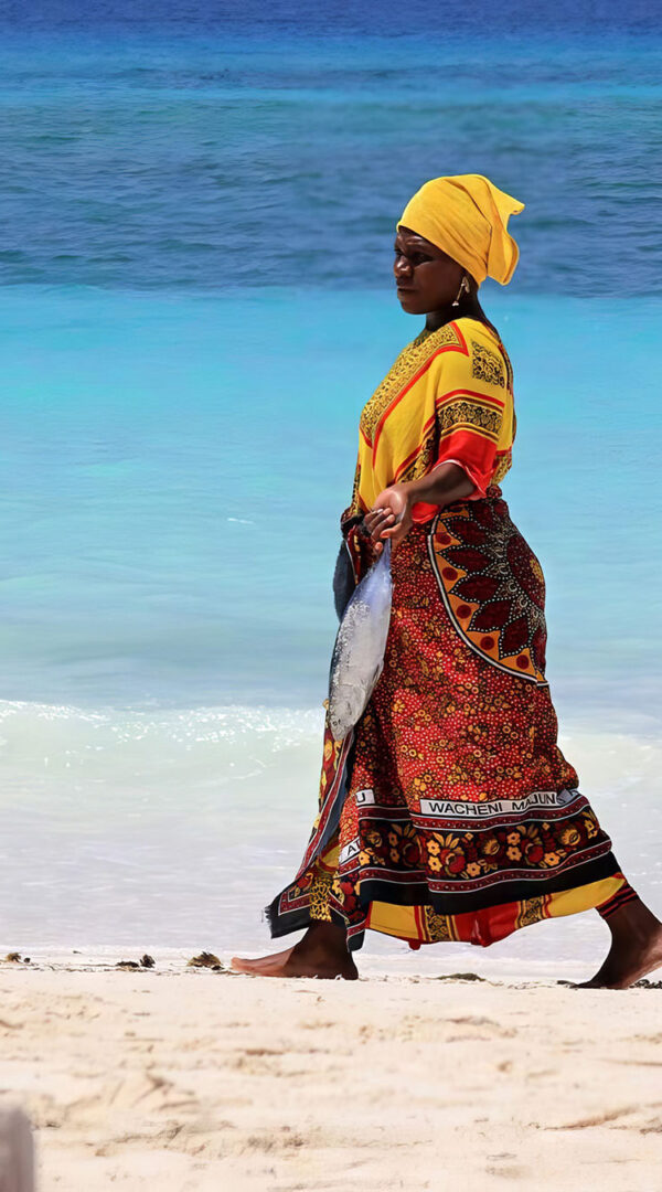 Local women walking on beach with traditional attire in Zanzibar Island