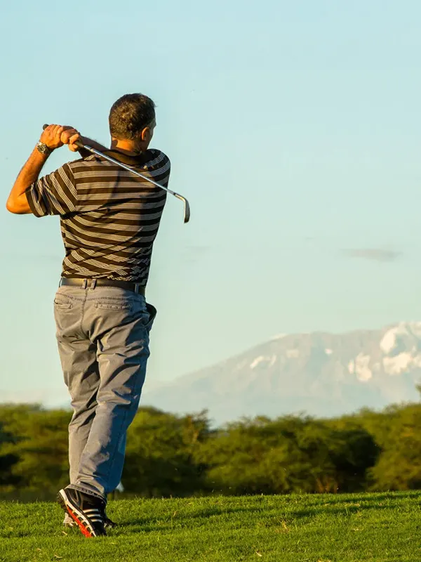 Golfer teeing off at Kilimanjaro Golf Course with Mount Kilimanjaro in the background during a luxury Tanzania safari